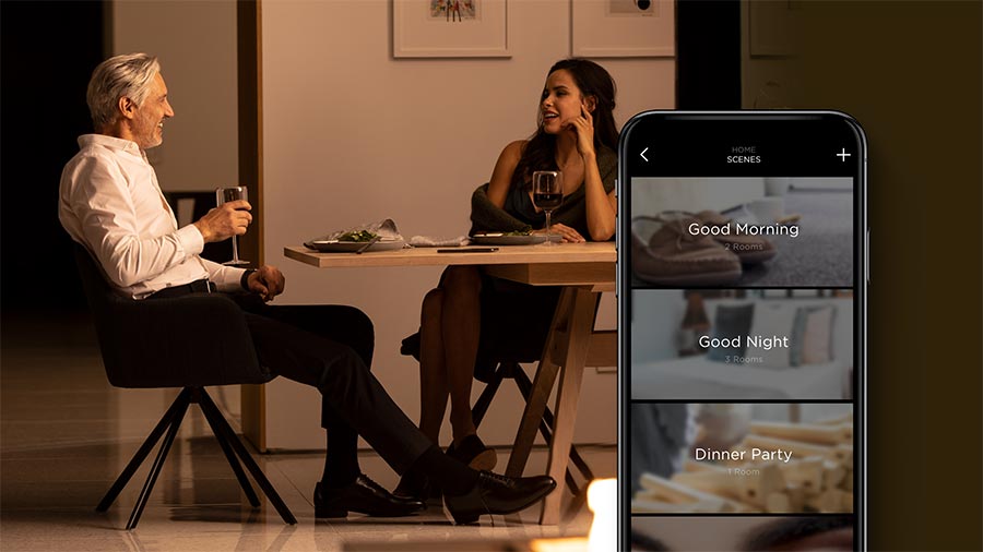 Couple at a dining table controlling home scenes on a smartphone