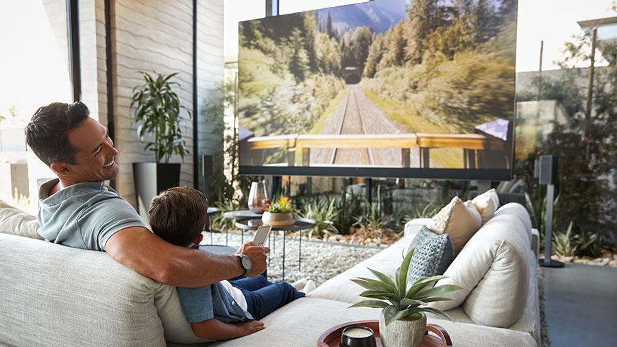Man and child watching a large home theater screen in a modern living room