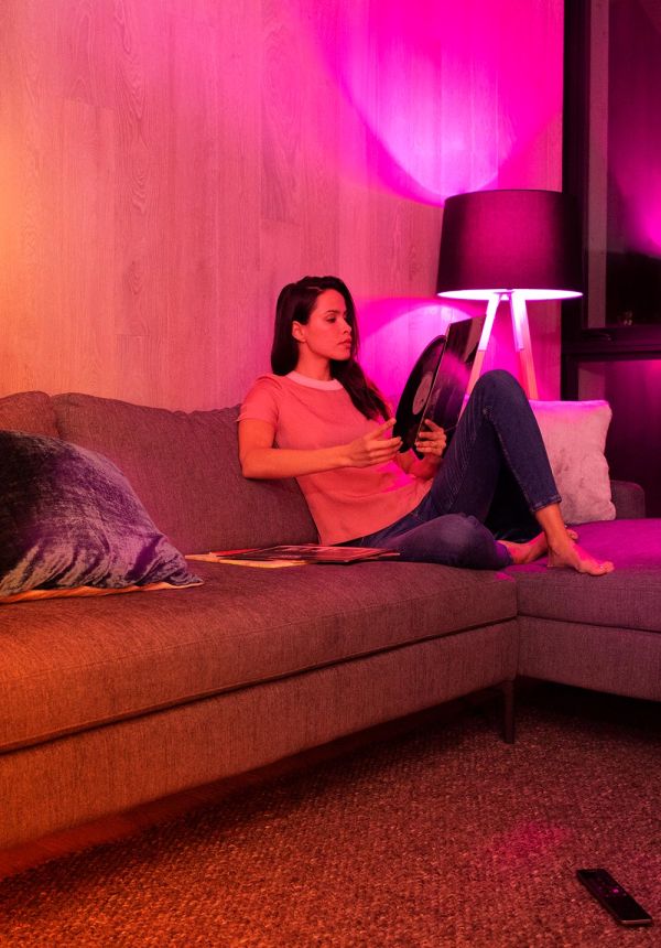 Woman sitting on a sofa reading under colorful accent lighting
